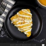 Carrot cake scone on a dark plate garnished with ground nutmeg and cinnamon.