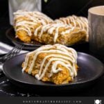 Carrot cake scone on a dark plate garnished with ground nutmeg and cinnamon.