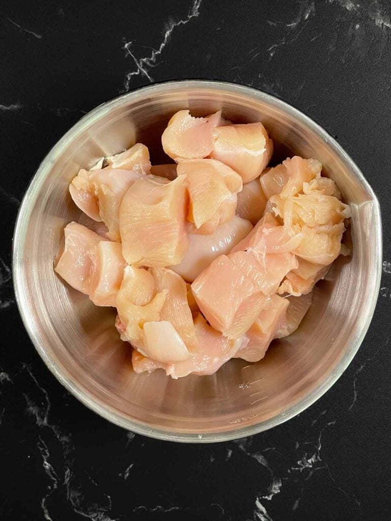 Raw chicken cut up in a bowl.