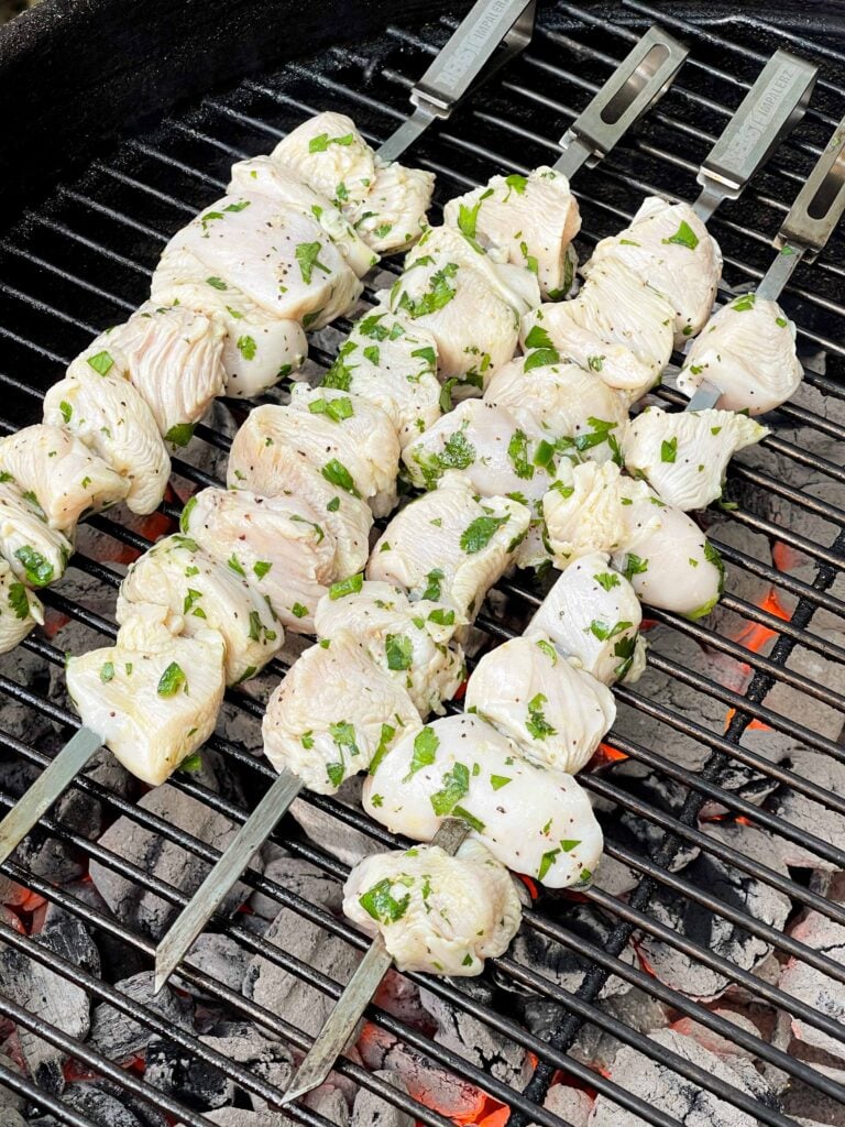 Chicken skewers just placed on a grill.