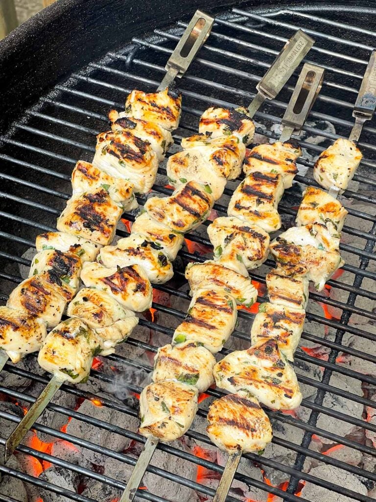 Chicken skewers grilling on a Weber grill.