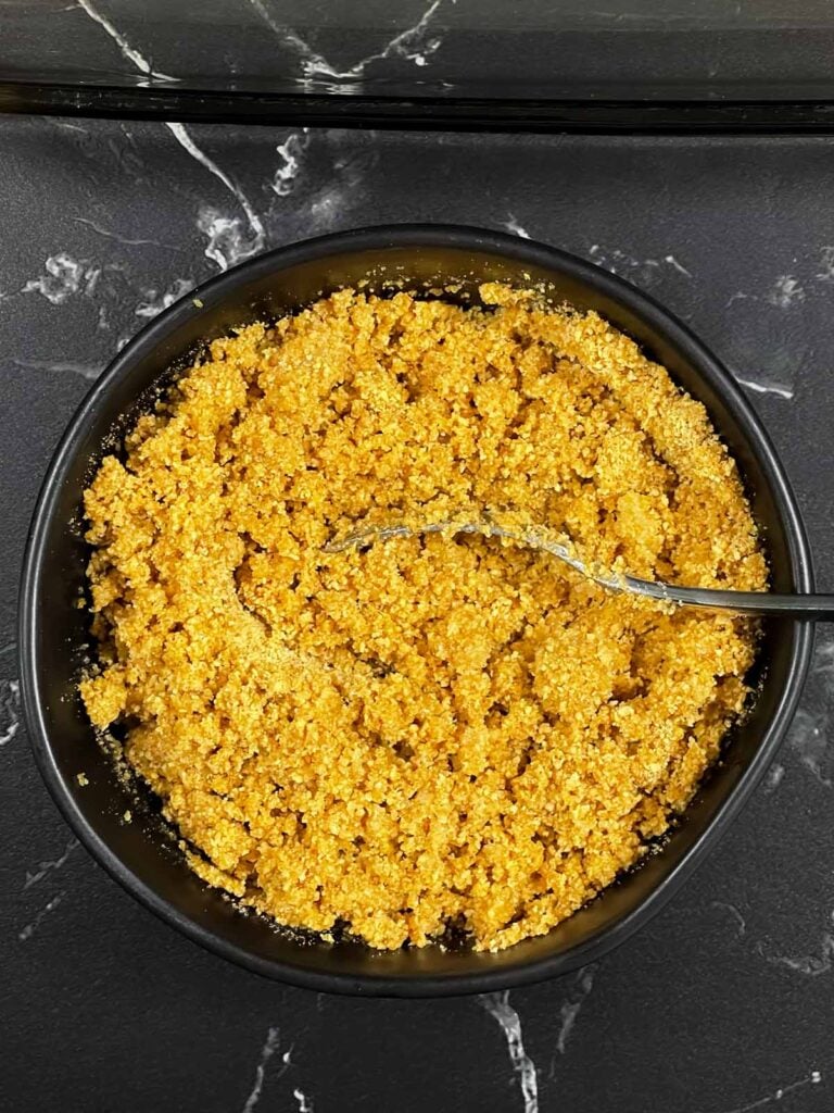 Graham cracker crust mixed in a bowl with a fork.