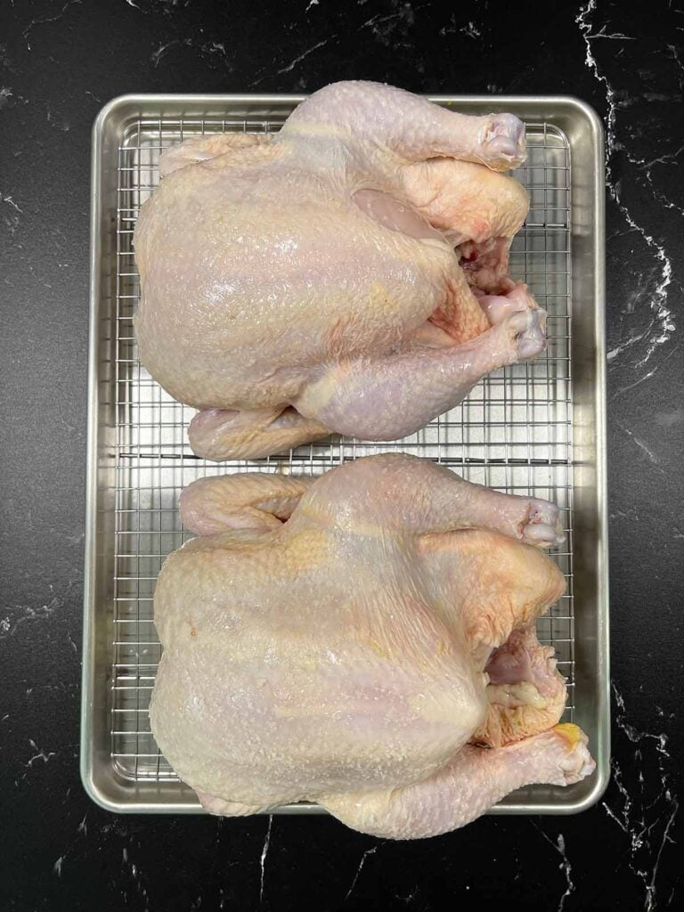 Two raw chickens on a wire rack.