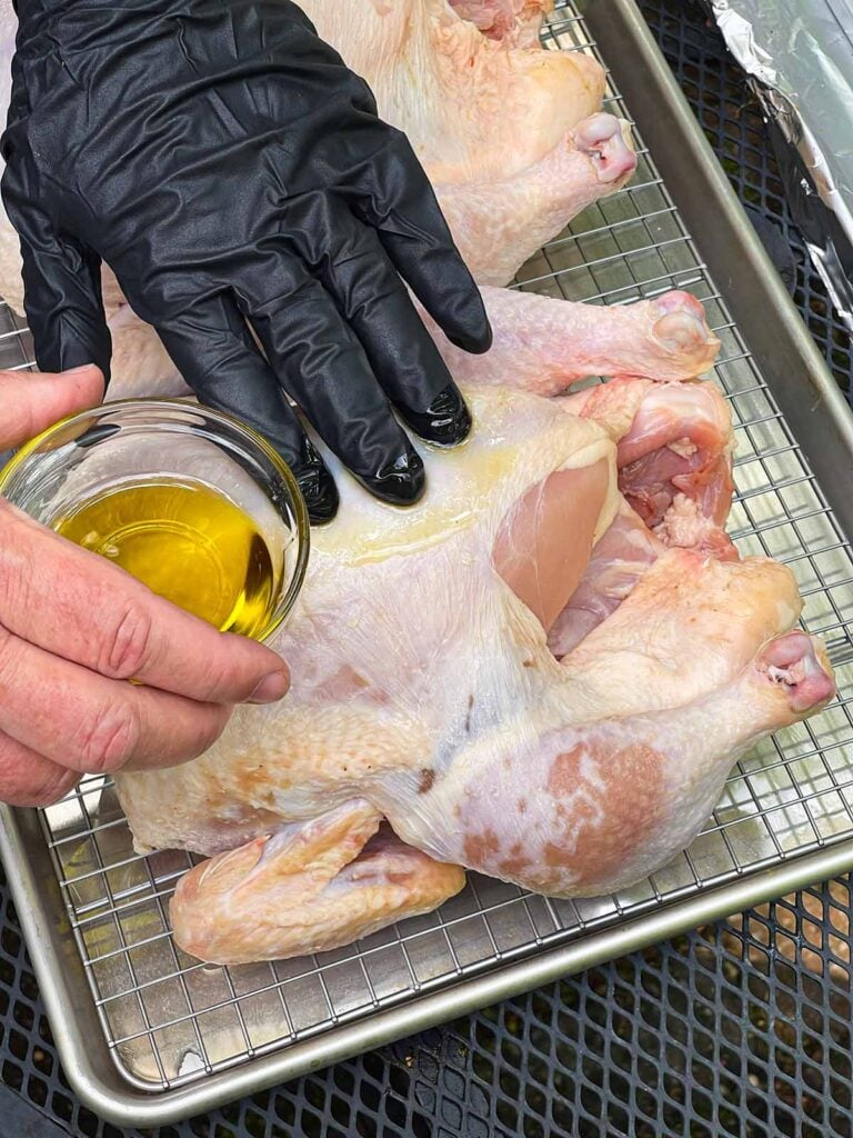 Applying oil onto a whole chicken.