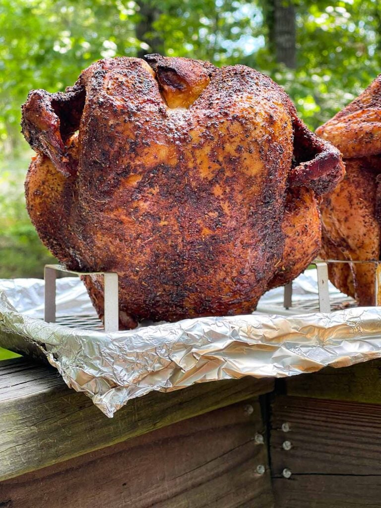 Two smoked chickens on a beer can stands.