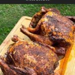 Two smoked chickens on a wooden cutting board.