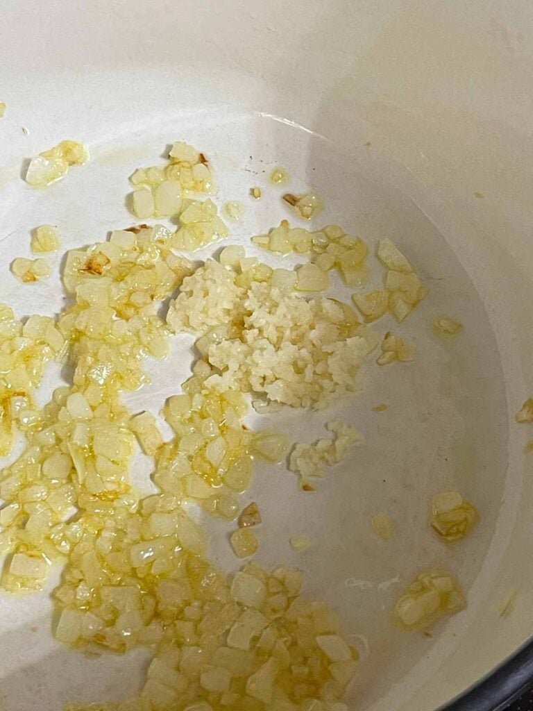 Garlic added to the cooked onions in a Dutch oven.