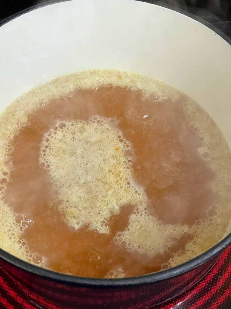 Chicken stock brought to a boil in the Dutch oven.