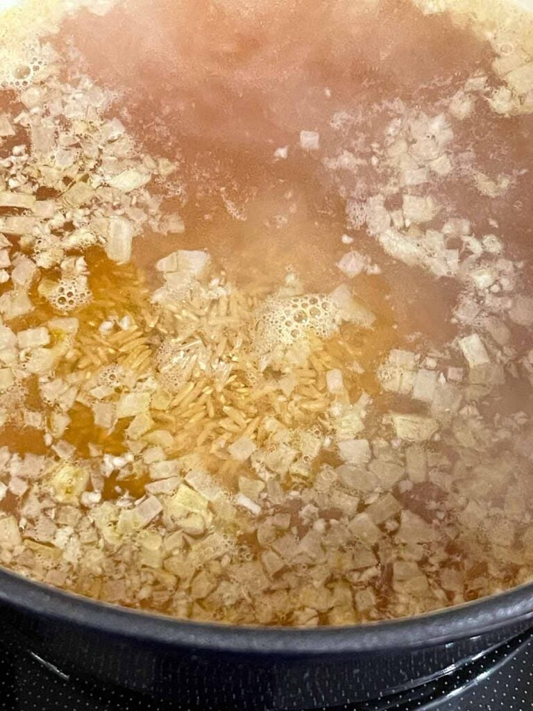 Brown rice stirred into the boiling chicken stock.