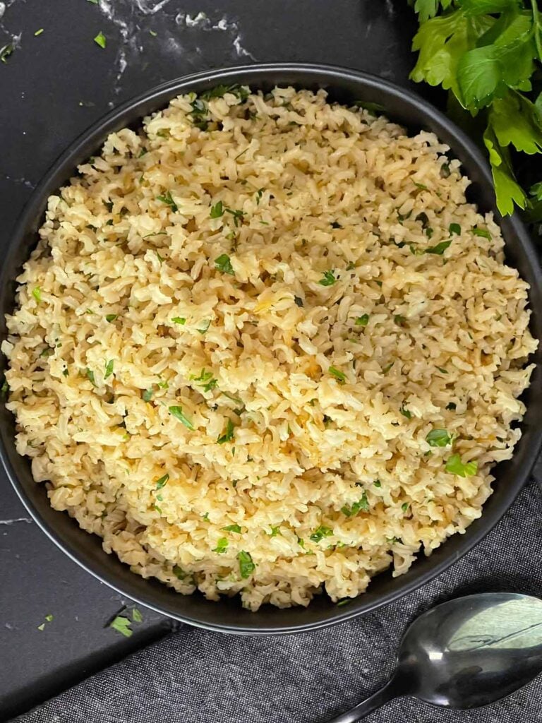 Baked brown rice served in a dark bowl.
