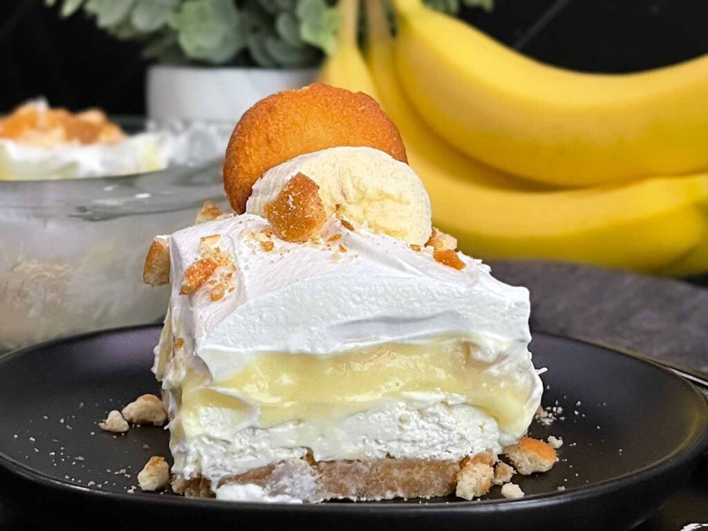 A serving of banana pudding lush on a dark plate.