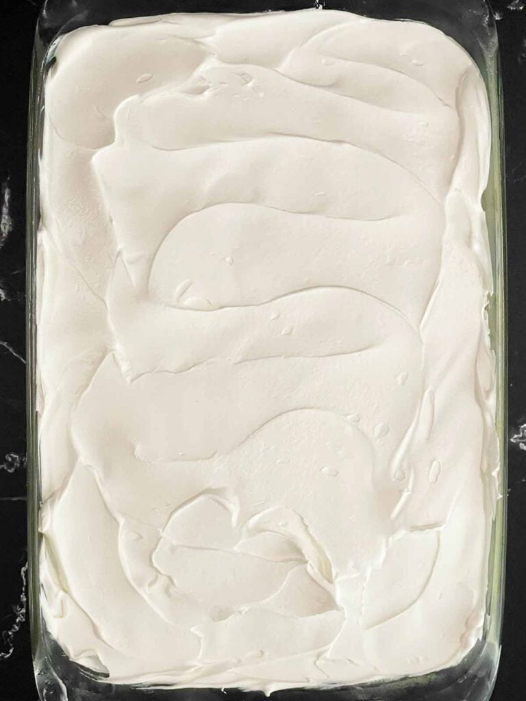 Whipped topping spread over the sliced bananas layer.