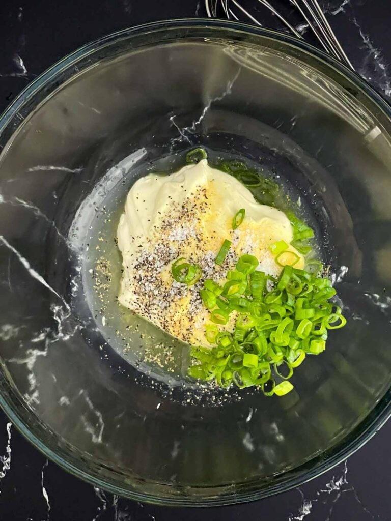 Mayonnaise, dill pickle juice, green onions, garlic powder, kosher salt, and black pepper in a glass mixing bowl.