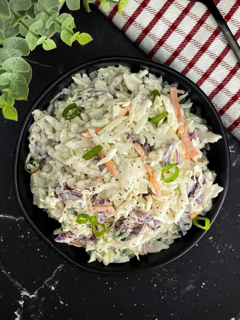 Creamy Classic Coleslaw in a black serving bowl made with coleslaw mix, green onions, and a tangy dill pickle dressing.