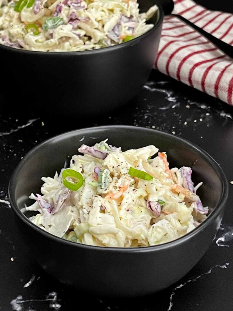 Bowl of Classic Coleslaw with crisp cabbage, carrots, and green onions in a creamy homemade dressing.