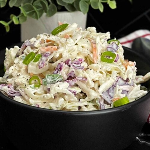 Bowl of Classic Coleslaw with crisp cabbage, carrots, and green onions in a creamy homemade dressing.