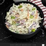 Creamy Classic Coleslaw in a black serving bowl made with coleslaw mix, green onions, and a tangy dill pickle dressing.