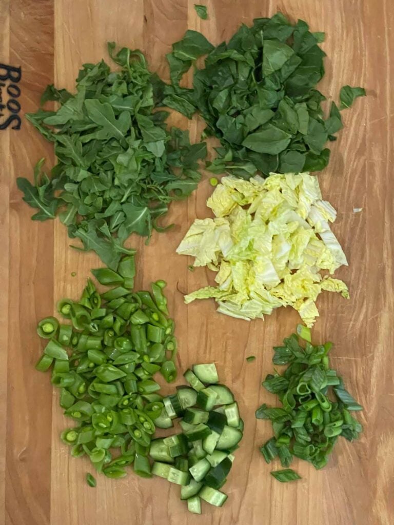 Chopped ingredients for the Green Goddess Salad on a wooden board.
