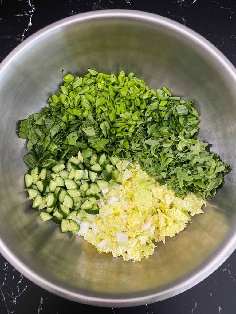 Chopped ingredients for the Green Goddess Salad in a large metal bowl.
