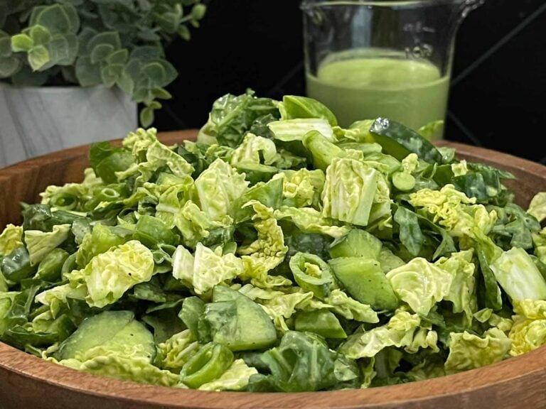 Green Goddess Salad in a wooden bowl with Napa cabbage, spinach, arugula, cucumbers, snow peas, and creamy herb dressing.