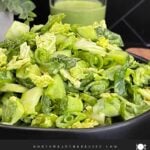 Green Goddess Salad in a black bowl with Napa cabbage, spinach, arugula, cucumbers, snow peas, and creamy herb dressing.