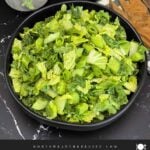 Green Goddess Salad served in a black bowl with Napa cabbage, spinach, arugula, cucumbers, snow peas, and creamy herb dressing.