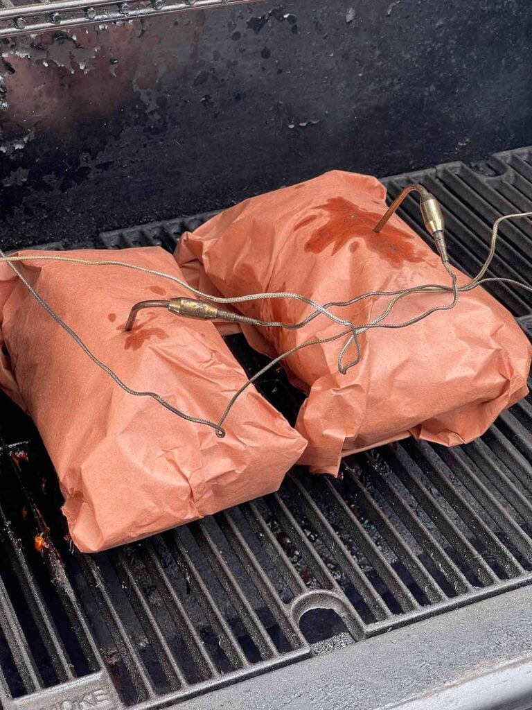 Boneless pork butt halves wrapped in pink butcher paper and returned to the smoker.