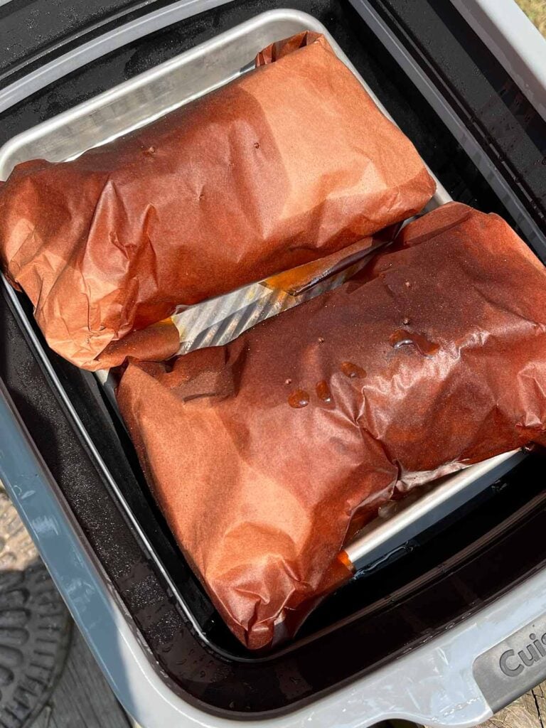 Wrapped smoked pork butt halves resting before shredding.
