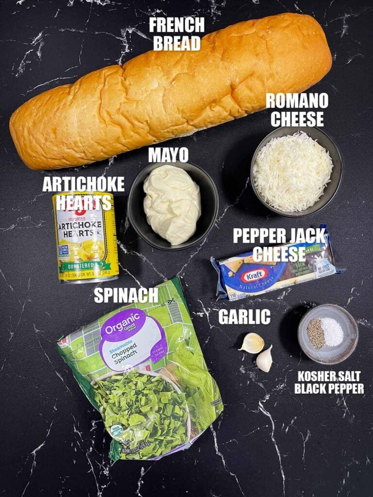 Spinach artichoke french bread pizza recipe ingredients on a dark surface.