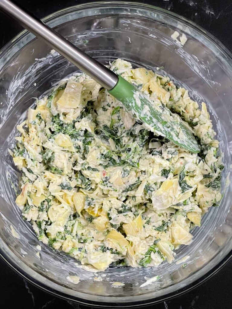 Spinach artichoke mixture in a large glass bowl.