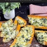Spinach artichoke French bread pizza sliced on a wooden board.