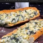 Spinach artichoke French bread pizza sliced on a wooden board.