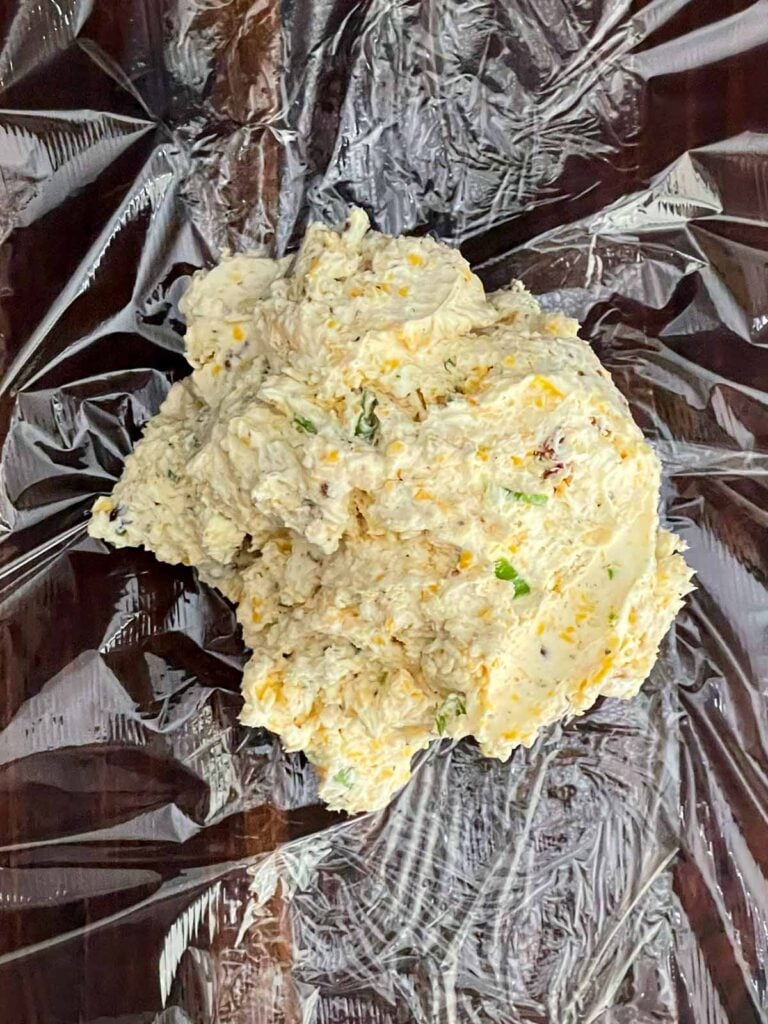 Cheese ball mixture dumped onto plastic wrap before shaping it into a ball before chilling.