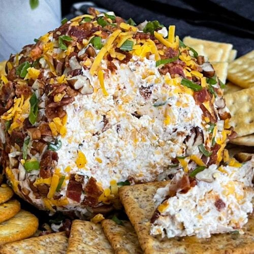 Close-up of a Bacon Cheddar Ranch Cheese Ball with a creamy cheddar center surrounded by crispy bacon and pecans.