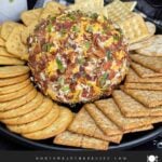 Bacon Cheddar Ranch Cheese Ball coated with bacon, pecans, cheddar cheese, and green onions served with crackers.