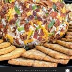 Bacon Cheddar Ranch Cheese Ball coated with bacon, pecans, cheddar cheese, and green onions served with crackers.