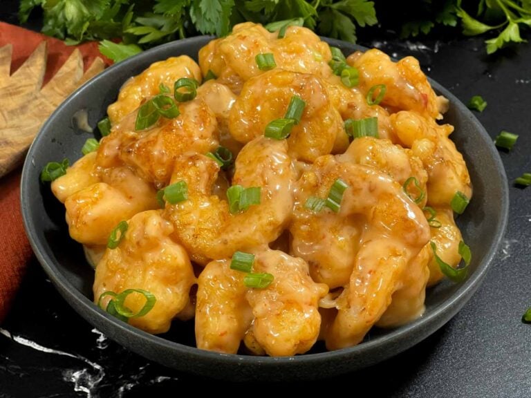 Homemade Bang Bang Shrimp served in a gray bowl and garnished with sliced green onions.