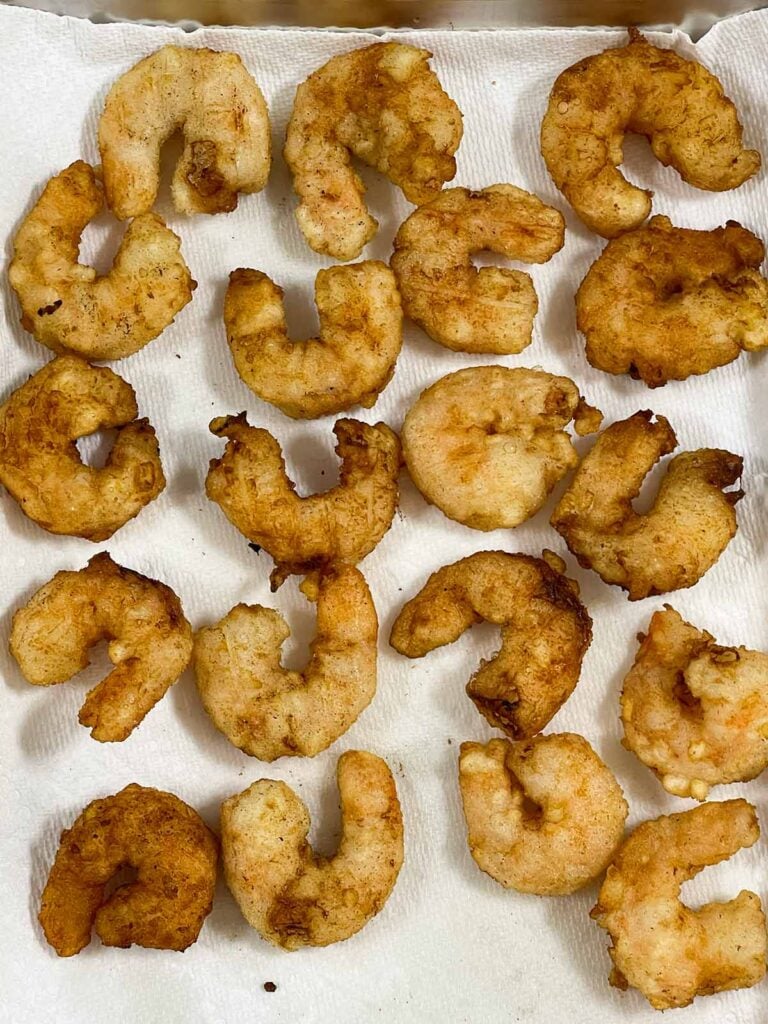Freshly fried shrimp draining on paper towels until crisp and golden brown.