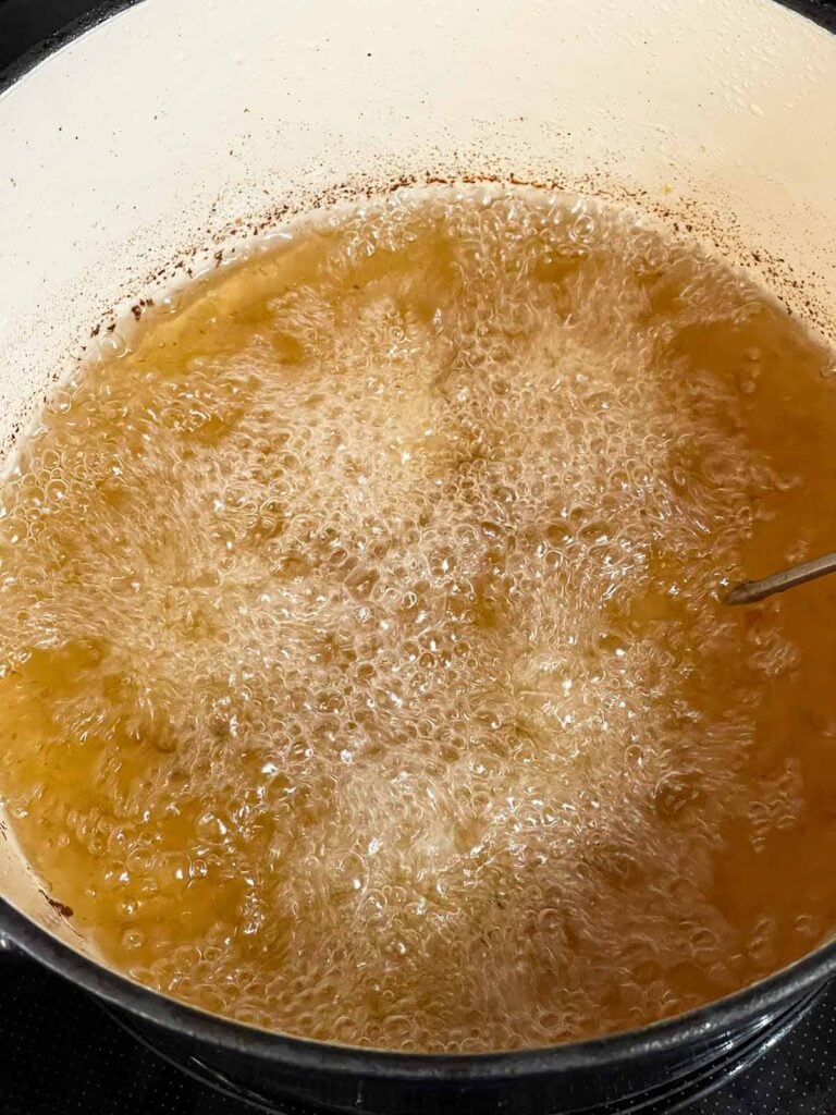 Shrimp frying in hot canola oil in a Dutch oven until crispy and golden.