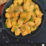Homemade Bang Bang Shrimp served in a gray bowl and garnished with sliced green onions.