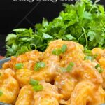 Homemade Bang Bang Shrimp served in a gray bowl and garnished with sliced green onions.