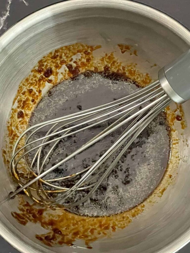Homemade fried rice sauce whisked together in a stainless steel bowl with soy sauce, Sriracha, sesame oil, and ginger.