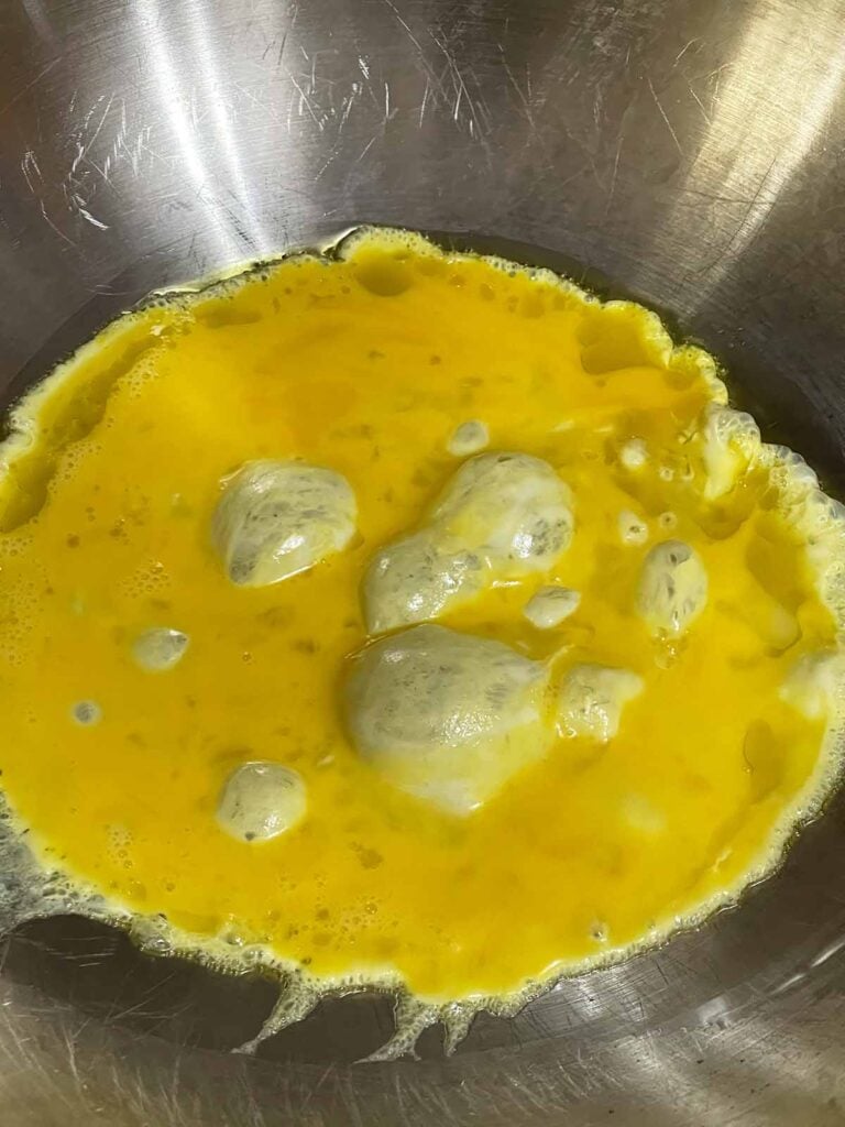 Eggs cooking in a hot wok for homemade brown fried rice.