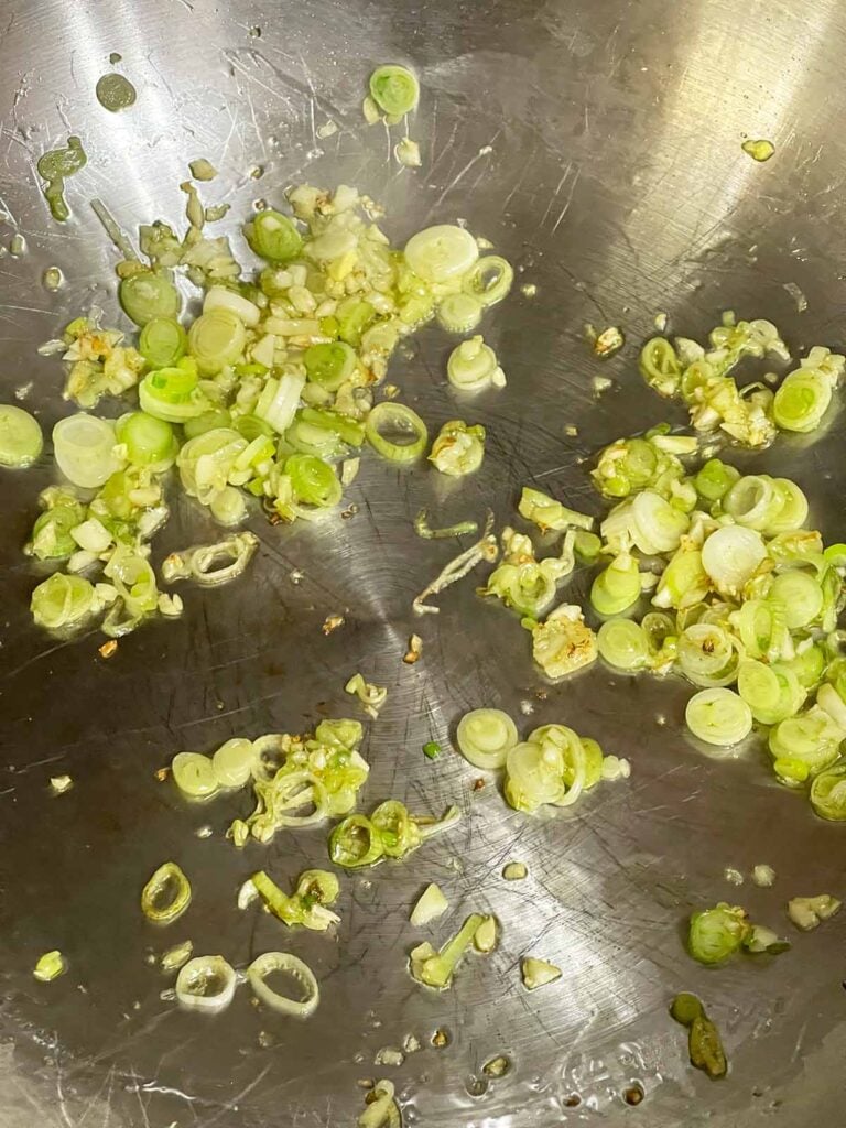 Garlic and green onions softened until fragrant in a hot wok.