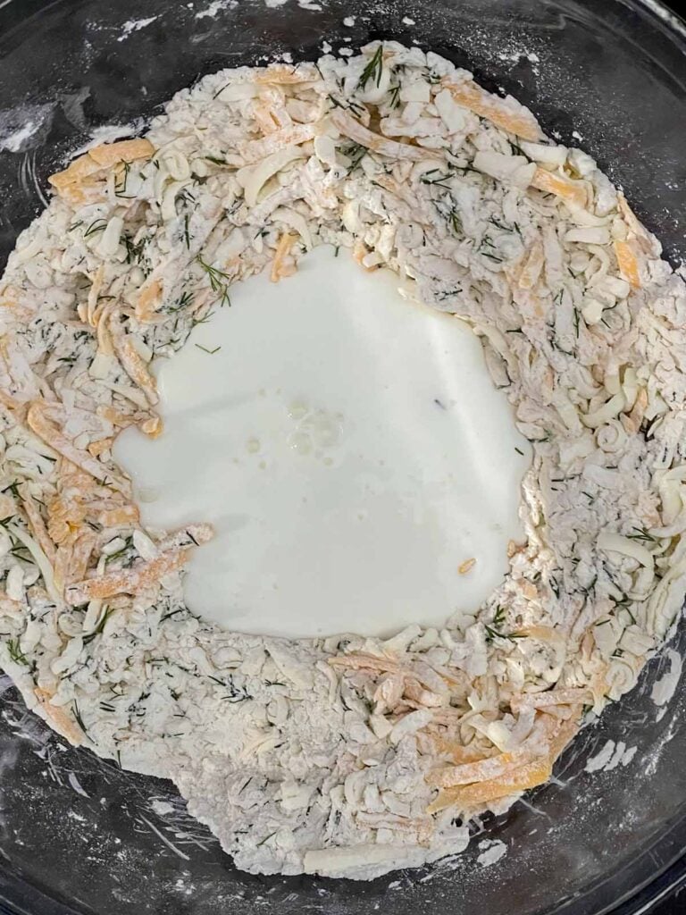 Buttermilk poured into the well of the biscuit dough ingredients.