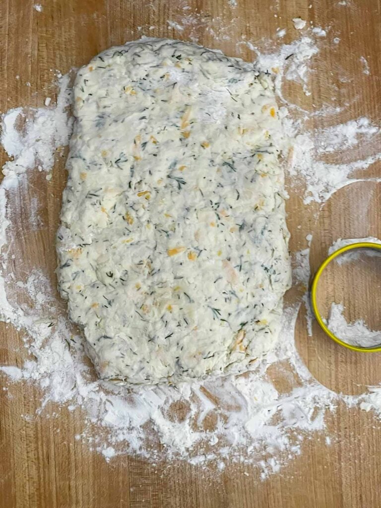 Cheddar dill biscuit dough patted into a rectangle on a well floured board.