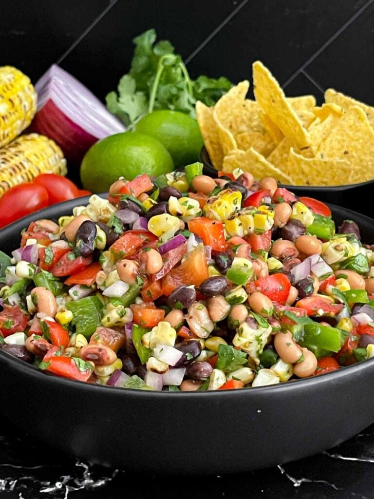 Colorful Cowboy Caviar made with black beans, black-eyed peas, corn, tomatoes, peppers, and cilantro.
