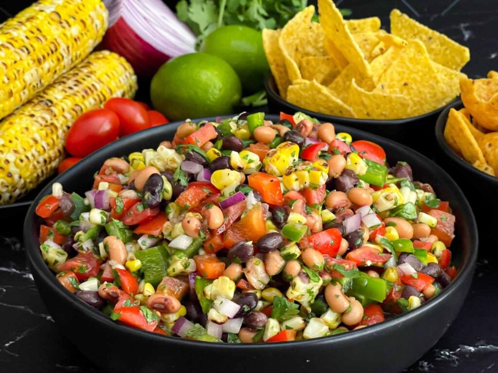 Easy Cowboy Caviar made with black beans, black-eyed peas, corn, tomatoes, peppers, and cilantro in a serving bowl.