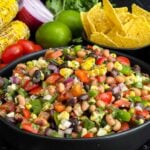 Easy Cowboy Caviar made with black beans, black-eyed peas, corn, tomatoes, peppers, and cilantro in a serving bowl.