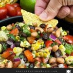 Tortilla chip scooping up Cowboy Caviar from a serving bowl.